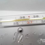 Broken thermometer with mercury droplets
