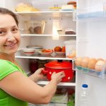 Woman putting a saucepan in the refrigerator
